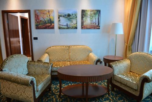 a room with couches and tables and paintings on the wall at Hotel Mellain in Tuzla