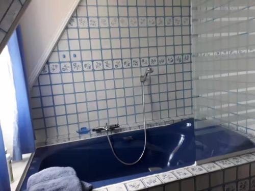 a bath tub with a hose in a tiled bathroom at Chambres d'Hôtes la BAKATA près de DEAUVILLE in Danestal
