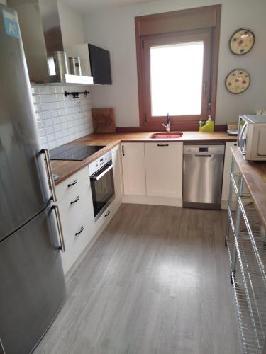 a kitchen with white cabinets and a wooden floor at Apartamento Buño Malpica in Malpica