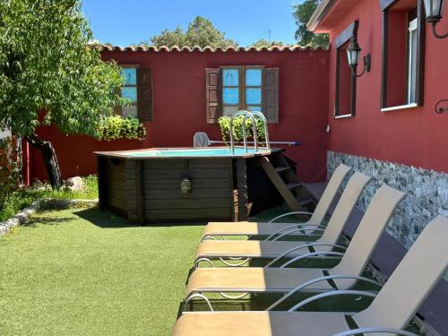 a group of chairs sitting on a lawn next to a red house at Casa Rural El Fresno in Burgohondo