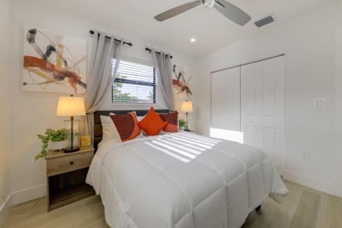 a white bedroom with a large white bed with orange pillows at 3 Mi to Hard Rock Stadium Retreat with Private Yard in Miramar
