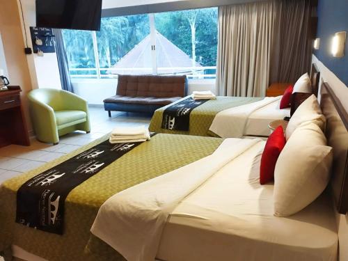 a hotel room with two beds and a chair at Hotel Puente Nacional & Spa in Puente Nacional