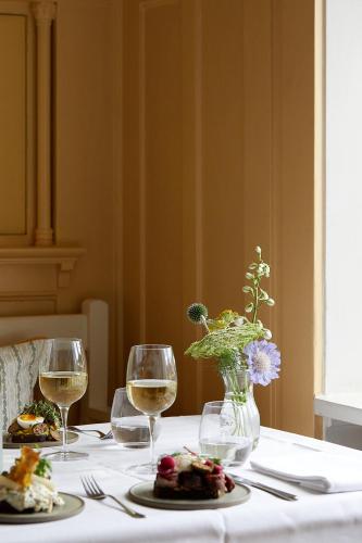 a table with two glasses of wine and a vase of flowers at Hotel Saxkjøbing in Sakskøbing