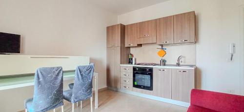 Una cocina con gabinetes de madera y sillas azules. en Sofia Kite Apartment, en Marsala