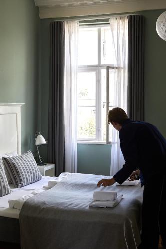 a woman putting towels on a bed in a room at Hotel Saxkjøbing in Sakskøbing