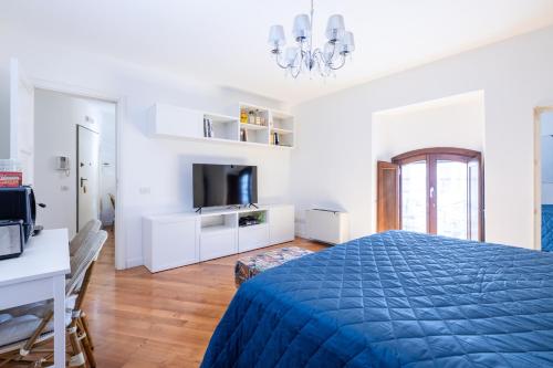 een witte slaapkamer met een blauw bed en een televisie bij Elegante dimora - nel centro di Roma in Rome
