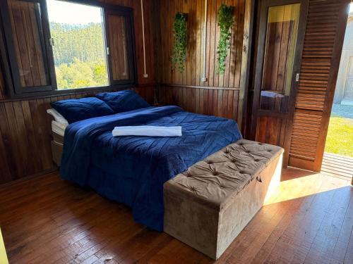 a bed with a blue comforter in a room at CABANAS BELVEDERE- SERRA DO RIO Do RASTRO in Louro Müller