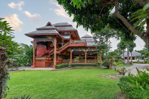 a house with a green lawn in front of it at Romsak Lanna Resort in Chiang Mai