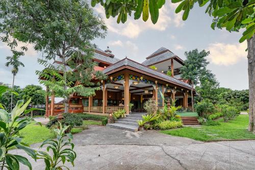 a large house with a porch and trees at Romsak Lanna Resort in Chiang Mai