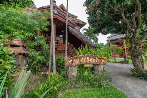 a sign in front of a house with a building at Romsak Lanna Resort in Chiang Mai