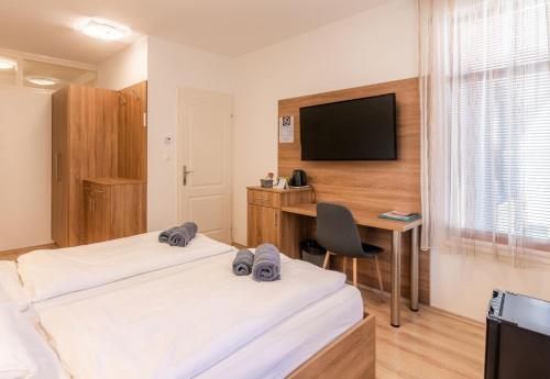a hotel room with two beds and a desk and a television at Citylife Rooms in Mosonmagyaróvár