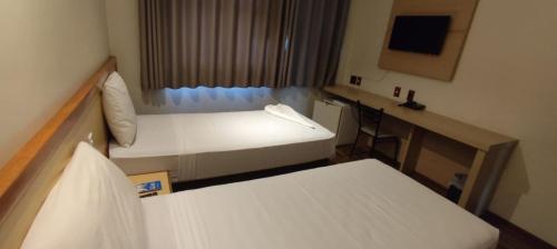 a small room with two beds and a desk at Pouso Alegre Hotel INN - Próximo a Unimed e Rodoviária in Pouso Alegre
