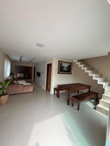 a living room with a table and a bed and stairs at House Portal Condomínio Portal de Arembepe! in Camaçari