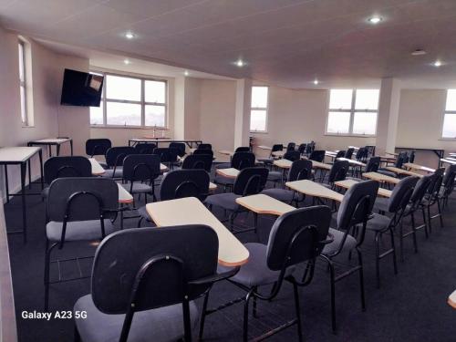 an empty classroom with desks and chairs in it at Pouso Alegre Hotel INN - Próximo a Unimed e Rodoviária in Pouso Alegre