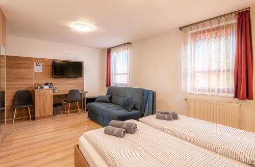 a hotel room with two beds and a couch at Citylife Rooms in Mosonmagyaróvár