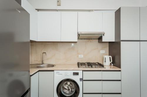 a kitchen with white cabinets and a washing machine at Aeroport Family Apartament in Codru
