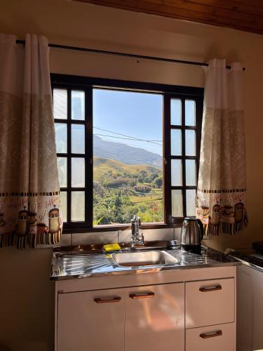 a kitchen with a sink and a window at Chalé Encanto da Serra in São Francisco Xavier
