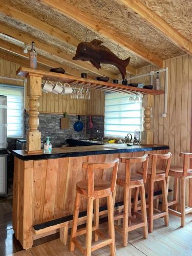 a kitchen with a counter with wooden chairs and a counter top at Cabaña By Casur in Panguipulli