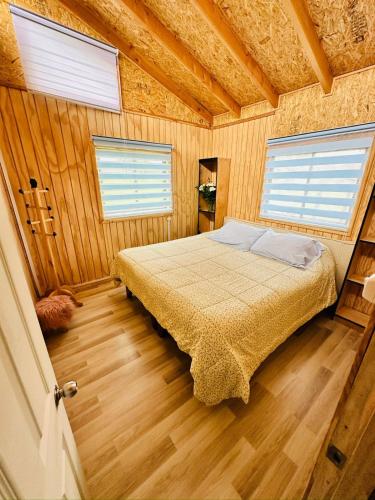 a bedroom with a bed in a room with wooden floors at Cabaña By Casur in Panguipulli
