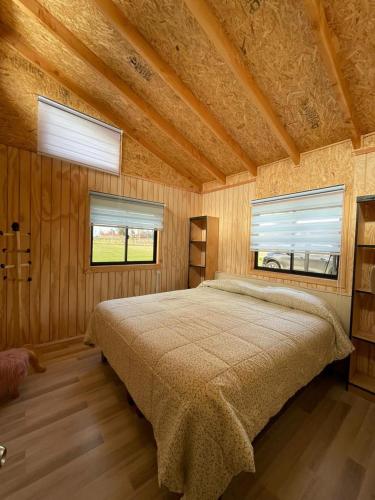a bedroom with a large bed and two windows at Cabaña By Casur in Panguipulli