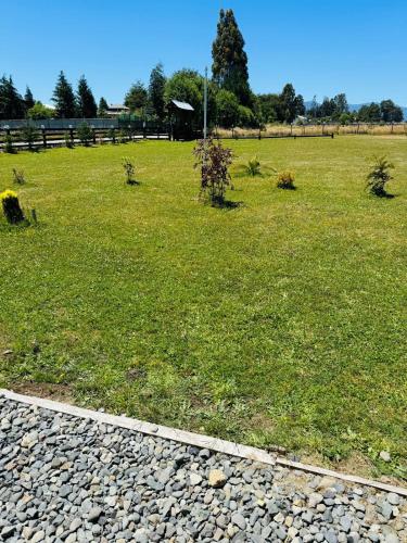 a grassy field with a fence and trees in it at Cabaña By Casur in Panguipulli