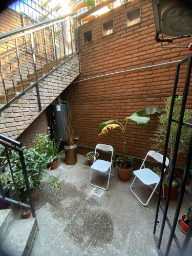 a patio with two chairs and a brick wall at Hostel Nueva cordoba Subte Uno in Cordoba