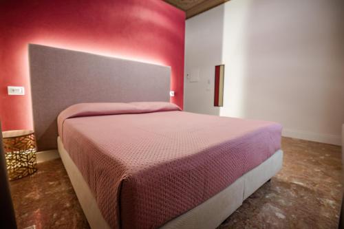 a bedroom with a bed with a red wall at Dimora Don Ciccillo B&B in Bagnara Calabra