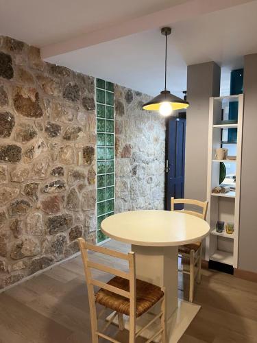 a table and chairs in a room with a stone wall at La Casona de Navaleno in Navaleno