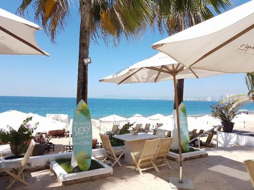 a beach with chairs and umbrellas and the ocean at Petit Bonheur - Calm Intimate - Terrace & Beach in Puerto Vallarta