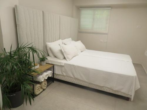 a bedroom with a bed with white sheets and a window at Gold House in Bet Shemesh