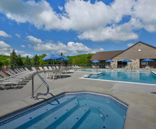 ein Pool in einem Resort mit Stühlen und Sonnenschirmen in der Unterkunft Seven Springs Hideaway Ski In and Out Pet Friendly in Champion