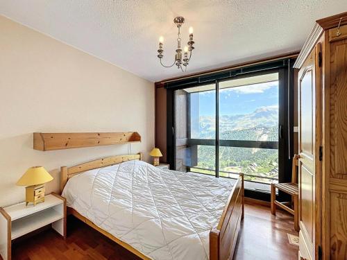 a bedroom with a bed and a large window at Résidence Pegase - APPARTEMENT 3 PIECES 7 PERSONNES PISTES MAE-9854 in Le Corbier