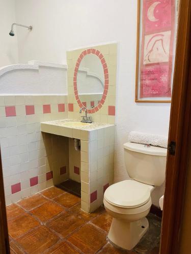 a bathroom with a toilet and a sink with a mirror at Hotel Casa FERNALI in Bernal