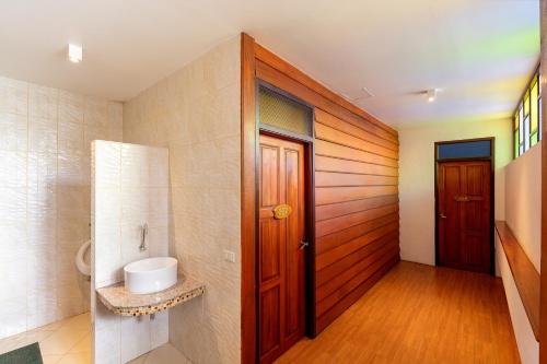a bathroom with a wooden door and a sink at Romsak Lanna Resort in Chiang Mai