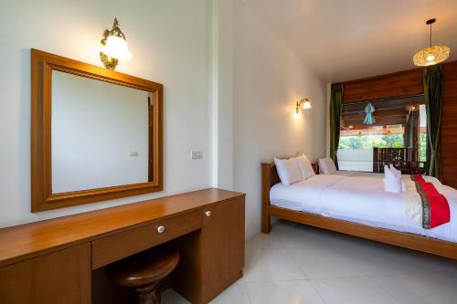 a bedroom with a bed and a large mirror at Romsak Lanna Resort in Chiang Mai