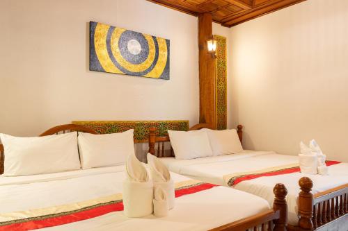 a room with two beds and a painting on the wall at Romsak Lanna Resort in Chiang Mai