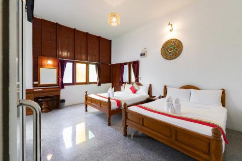 a bedroom with two beds and a desk in it at Romsak Lanna Resort in Chiang Mai