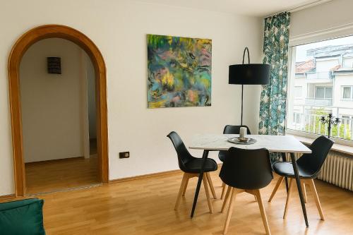 a dining room with a table and chairs and a painting at Elegante Designwohnung mit Balkon 15min Airport und Parken in Offenbach