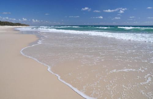a sandy beach with waves coming in from the ocean at Fairways Golf & Beach Retreat Bribie Island in Woorim