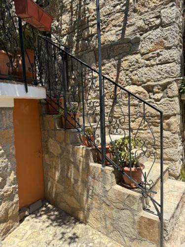 a stone wall with a staircase with potted plants at Vigliata Sidirounta Traditional Stonehouse in Chios