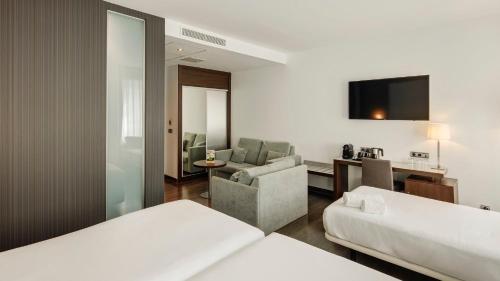 a hotel room with two beds and a living room at Sercotel Coliseo in Bilbao