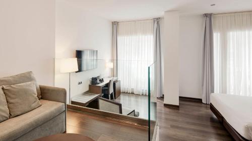 a living room with a couch and a mirror at Sercotel Coliseo in Bilbao