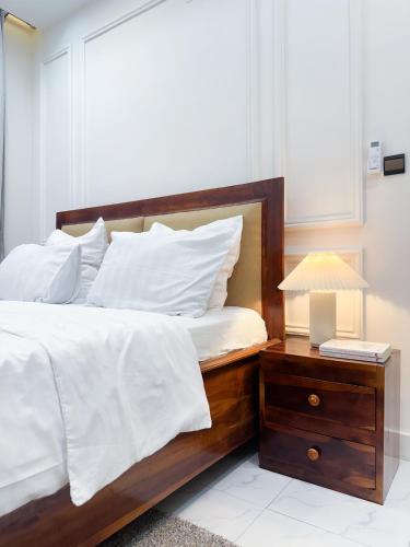 a bed with white sheets and a table with a lamp at La brise Marine in Lomé