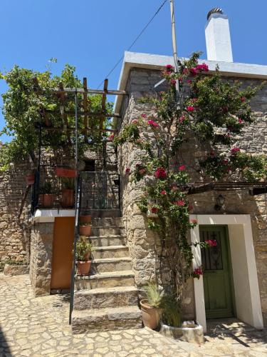 a stone building with stairs and flowers on it at Vigliata Sidirounta Traditional Stonehouse in Chios