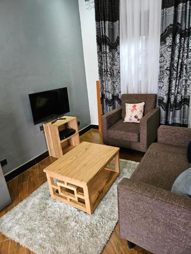 a living room with a tv and a coffee table at Jopet Apartments in Fort Portal