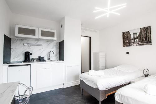 Dieses weiße Zimmer verfügt über 2 Betten und eine Küche. in der Unterkunft Sweet-Thermal Amnéville loisir, parking gratuit in Amnéville