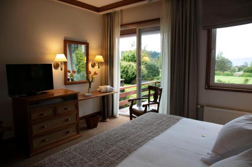 a hotel room with a bed and a television and a window at Hotel Termas Puyehue Wellness & Spa Resort in Puyehue