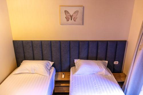 a bedroom with two beds and a butterfly picture on the wall at Sofra Kelmendit in Tamarë