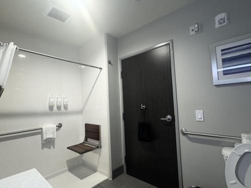 a bathroom with a toilet and a black door at La Quinta by Wyndham Opelika Auburn in Opelika
