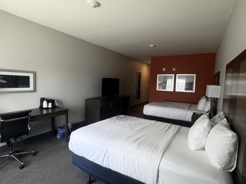 a hotel room with two beds and a desk at La Quinta by Wyndham Opelika Auburn in Opelika